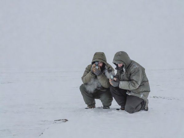 Two field photographers checking a sighting compass and GPS during flat overcast whiteout conditions